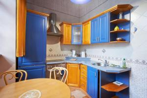 a kitchen with blue cabinets and a wooden table at Cozy Apartment in Gothic style house in the Heart of the Old Town in Vilnius