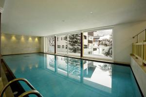 a swimming pool in a house with a large window at Hotel Italia in Corvara in Badia