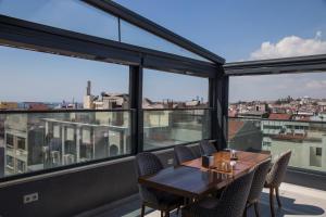 comedor con mesa, sillas y ventanas grandes en Meretto Hotel LALELİ en Estambul