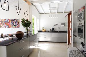 uma cozinha com armários brancos e um lavatório em Le Talisman em Goyave