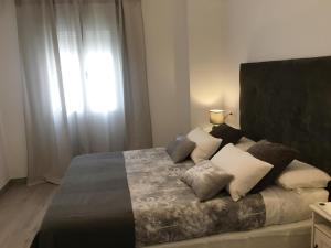 ein Schlafzimmer mit einem Bett mit Kissen und einem Fenster in der Unterkunft Apartamento San José by CasaTuristica in Ronda