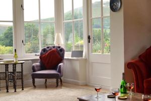 a living room with a chair and a table and windows at The Oaks in Church Stretton
