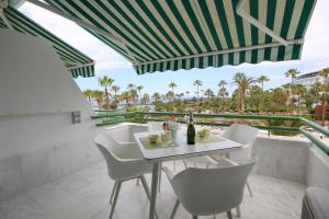 Luxury Apartments in first beach line with pool في أديخي: طاولة بيضاء وكراسي على شرفة بها نخيل