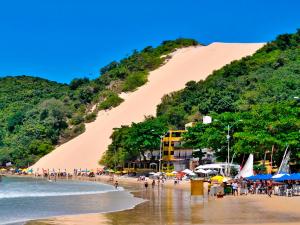 a beach with people and a large sand dune at Oxente Travel Apart Hotel in Natal