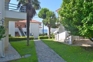 a walkway in front of a house with a palm tree at HALKIDIKI MΑRE in Kalivia Poligirou