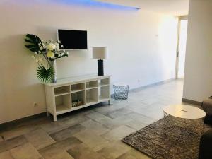 una sala de estar con TV y un jarrón de flores en Orange Studio, en Vilamoura