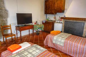 a kitchen with two beds and a tv and a desk at Bed and Breakfast Le Quattro Stagioni in Neirone