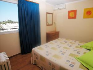 1 dormitorio con 1 cama con cortina azul y ventana en Apartamentos Ebusus, en Santa Eulària des Riu