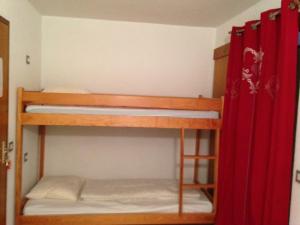 Ce dortoir comprend 2 lits superposés et des rideaux rouges. dans l'établissement L appart' du bonheur, à Ancelle