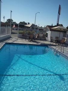 a large blue swimming pool with chairs and tables at Holiday Motel Oakdale in Oakdale