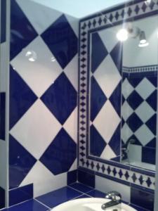 uma casa de banho com paredes em azulejos azuis e brancos e um espelho. em Les Restanques em Goult