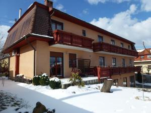 ein Haus mit Balkon im Schnee in der Unterkunft Edelweiss Panzió in Pilisvörösvár