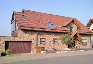 a brick house with a red roof and a garage at Ferienwohnung Familie Slepitzka in Niedenstein