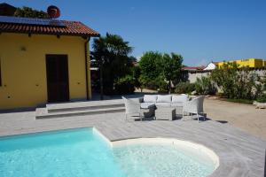 una piscina con sillas, una mesa y una casa en Residence Le Palme, en Torrazza Piemonte