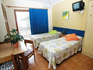 a room with two beds and a tv and a balcony at Apartamentos Ebusus in Santa Eularia des Riu