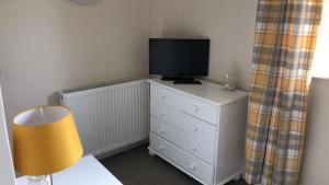 a bedroom with a television on a dresser with a lamp at 1 Silkin Serviced Accommodation in Newton Aycliffe