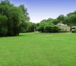 a large green field with a building and trees at Fervenza Casa Grande & Restaurante in Reguengo
