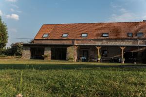 une maison en briques avec un toit rouge sur un champ dans l'établissement Au Petit Canteleu - Bed & Breakfast, à Beloeil