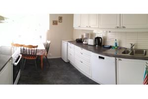 cocina con armarios blancos, fregadero y mesa en Apartment in Herand, Hardanger, en Herand