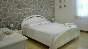 una camera con un letto bianco e un muro in pietra di Favignana Like Home a Favignana