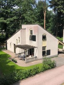 een klein wit huis met een veranda en een patio bij Huusje18 in Nunspeet