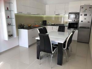 a kitchen with a white table and black chairs at Casa Leny in Tohanu Nou