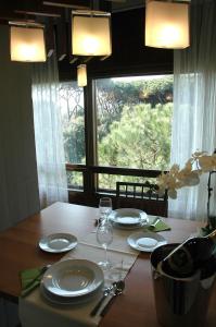 un tavolo con piatti e bicchieri da vino e una finestra di Prestigioso appartamento Lagomare a Torre del Lago Puccini