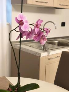 a vase with purple flowers on a table in a kitchen at Marina Centro Suite in Rimini +70 photos