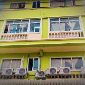 a yellow house with windows and a balcony at Natcha Place Rangsit Donmuang in Ban Talat Rangsit