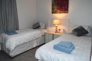 a bedroom with two beds and a table with a lamp at Adelaide Apartments 2 in Blackpool