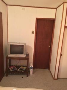 a room with a television and a table with a door at Hostería Bilbao in Villarrica