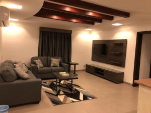 a living room with two couches and a flat screen tv at Villa Hotel Apartments Al Khobar in Al Khobar