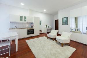 uma cozinha com armários brancos e uma mesa e cadeiras em Flores Studio no Porto