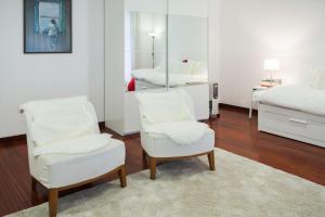 - une chambre avec 2 chaises blanches et un miroir dans l'établissement Flores Studio, à Porto