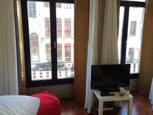 - une chambre avec un lit et une télévision sur une table dans l'établissement Flores Studio, à Porto