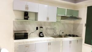cocina con armarios blancos, fregadero y microondas en Departamento Privado 3 recamaras, en Ciudad de México