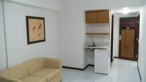 sala de estar con sofá y cocina pequeña en Araçá Flat 106, en Natal