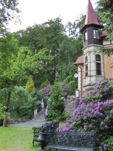 una casa con una torre del reloj y un banco en un jardín en Romantic Chateau Krasna Lipa, en Krásná Lípa