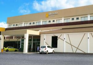 une voiture blanche garée devant un hôtel dans l'établissement Angsoka Hotel, à Teluk Intan