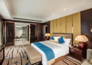 a bedroom with a large bed and a desk and lamp at Expo Center Hotel in Yiwu
