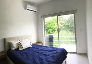 a bedroom with a blue bed and a large window at Hermosa Casa Vacacional Puerto Morelos in Puerto Morelos +12 photos