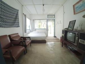 sypialnia z łóżkiem, telewizorem i kanapą w obiekcie Ban Narai River Guesthouse w mieście Chiang Mai