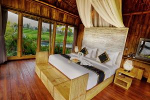 um quarto com uma cama num quarto com janelas em Padi Bali Eco Villas em Payangan