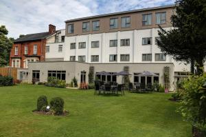 a large white building with tables and chairs in a yard at Best Western Plus Pinewood Hotel, Manchester Airport South Handforth in Handforth