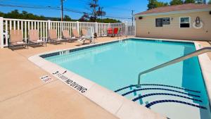 a swimming pool with chairs and a house at Best Western Plus Harrisburg Mechanicsburg in Enola