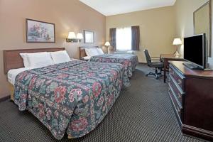 a hotel room with two beds and a desk and a television at Days Inn by Wyndham Collinsville St Louis in Collinsville