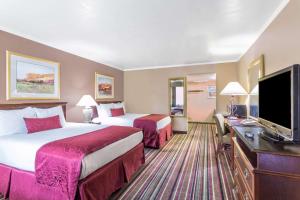 a hotel room with two beds and a flat screen tv at Days Inn & Suites by Wyndham Logan in Logan