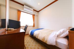 a bedroom with a bed and a desk with a television at Business Hotel Star in Beppu +11 photos