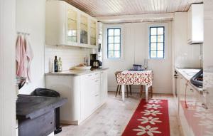 a kitchen with white cabinets and a table with a red rug at Ljunghusen in Höllviken