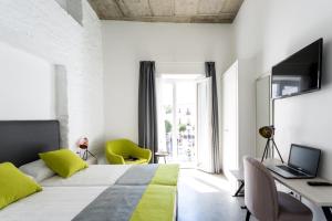 a bedroom with a bed and a desk with a laptop at La Puerta de Palacio - Adults Only in Seville